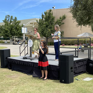 Geology Instructor and Co-Chair of the Gay-Straight Alliance Club Michelle Selvans speaks to students from stage. Sign language interpreter translates offstage. 