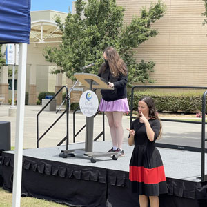 Speaker Morgan, Student Advocate, shares from stage. Sign Language Interpreter translates offstage.