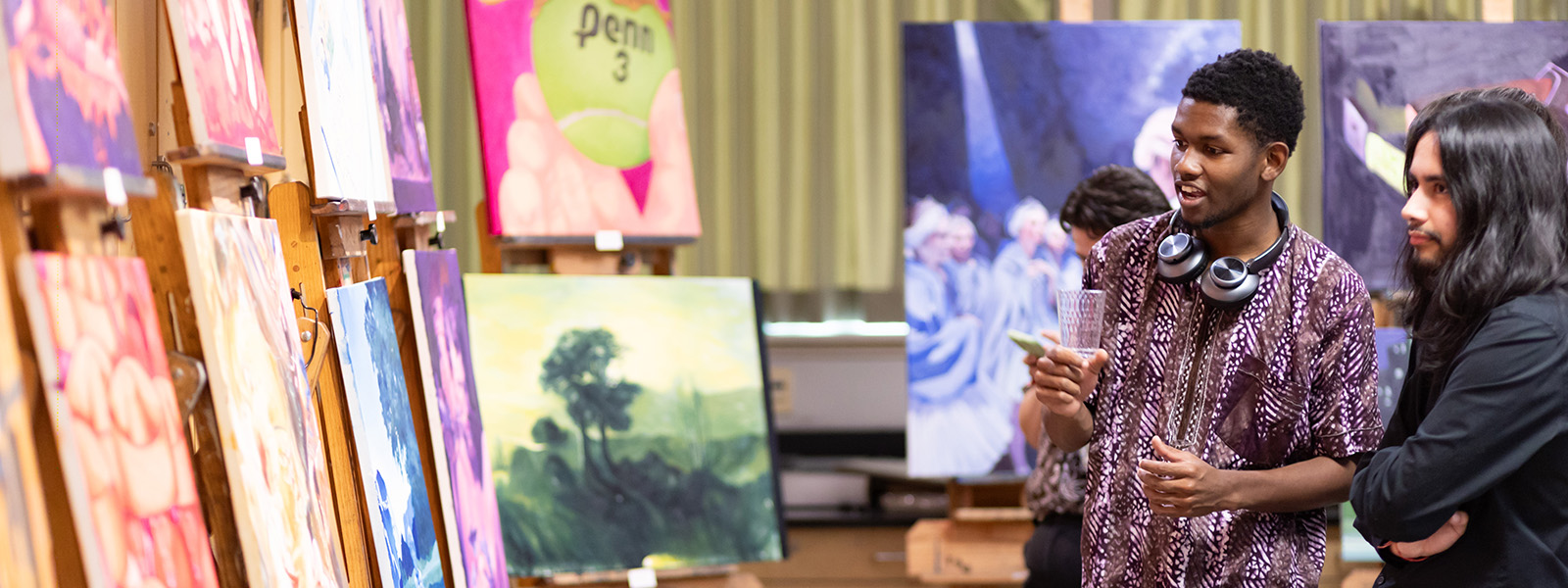 Two students discussing an artwork at a student art showcase