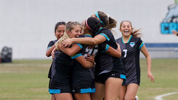 Female soccer athletes huddling in celebration