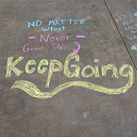 The words Keep going written in sidewalk chalk