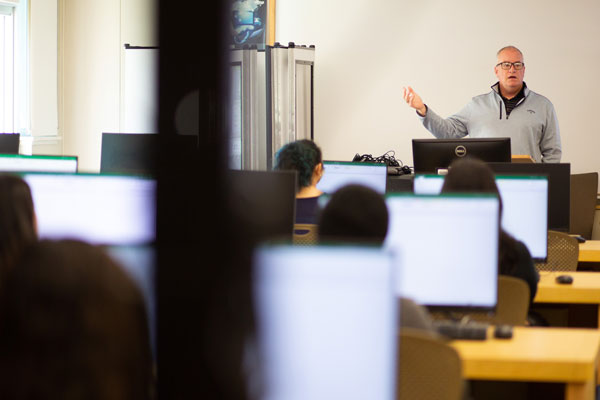 Professor teaching class of students in computer lab