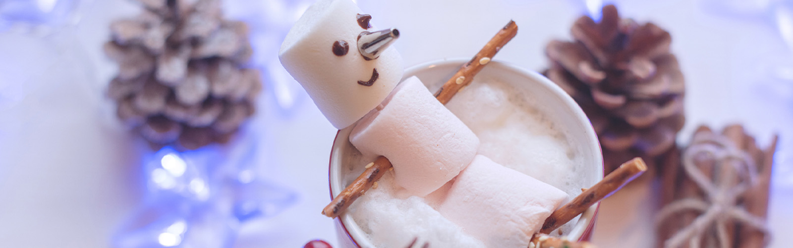marshmallow snowman laying on top of cup of hot chocolate
