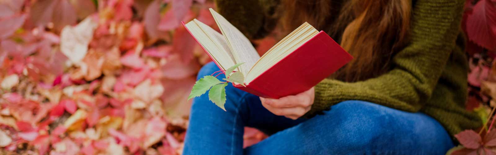 student reading a book and fall leaves