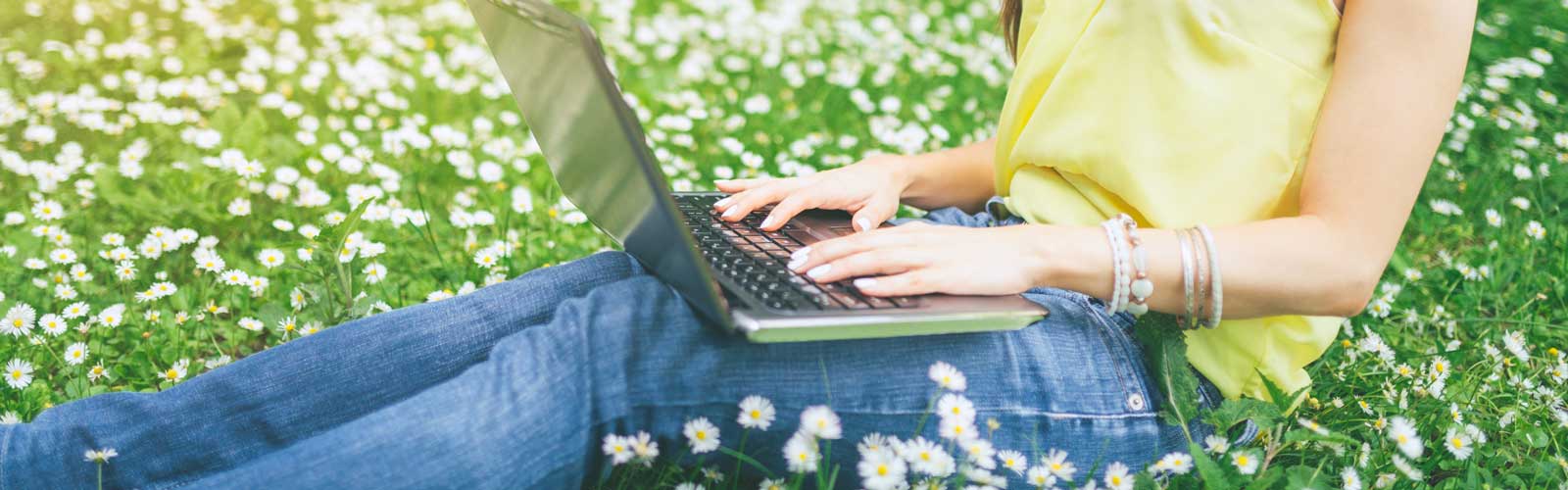 girl on laptop in summer field