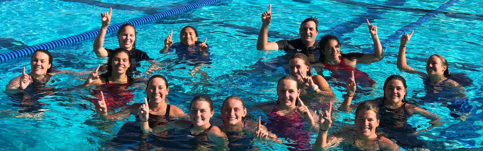The Women's Swim Team and Coach Mark Bennett celebrate their victory.