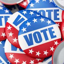 A tabletop of badges with the American flag and the word, "vote"