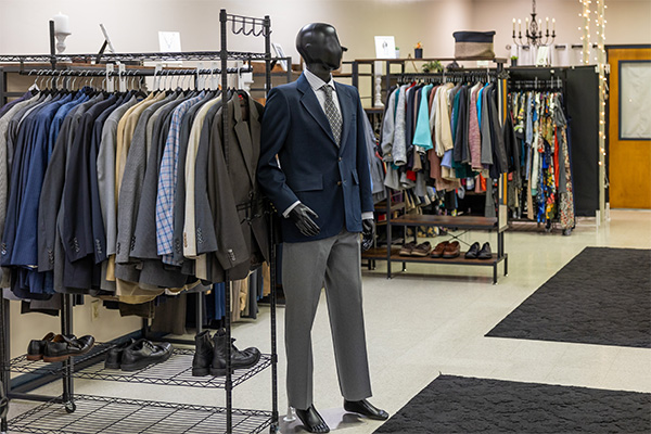 mannequin in front of a rack of suit jackets