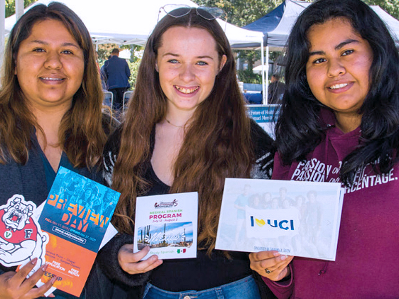 Three female students holding college transfer brochures