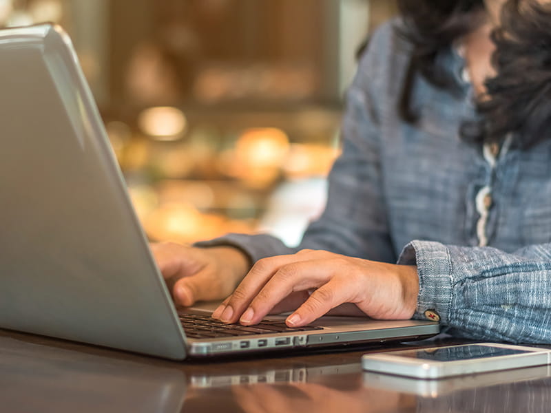 close-up of a woman's hands typing on a laptop