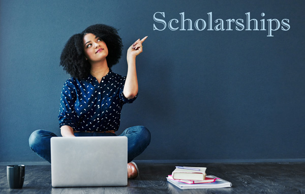 female student pointing to letters spelling out the word scholarships