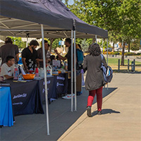 A student walking past a row of stands, each representing a club