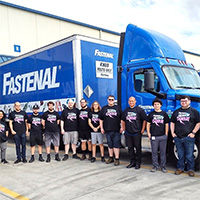 People standing in front of a blue Fastenal truck