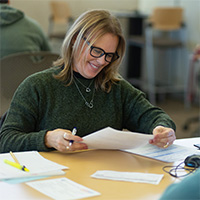 Woman in Computer Lab smiling and looking at papers