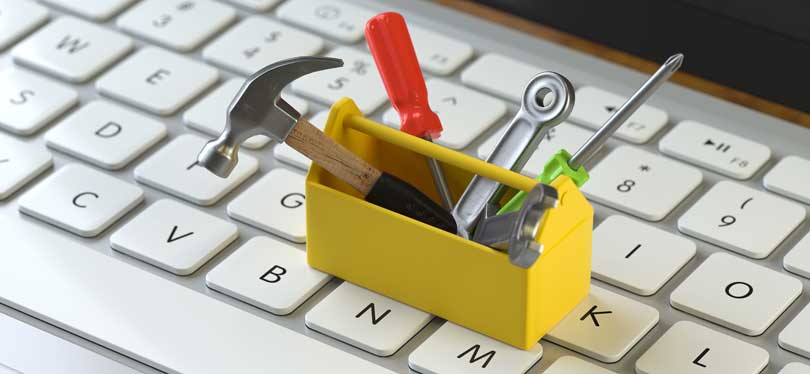 A yellow toolbox on computer keyboard full of tools