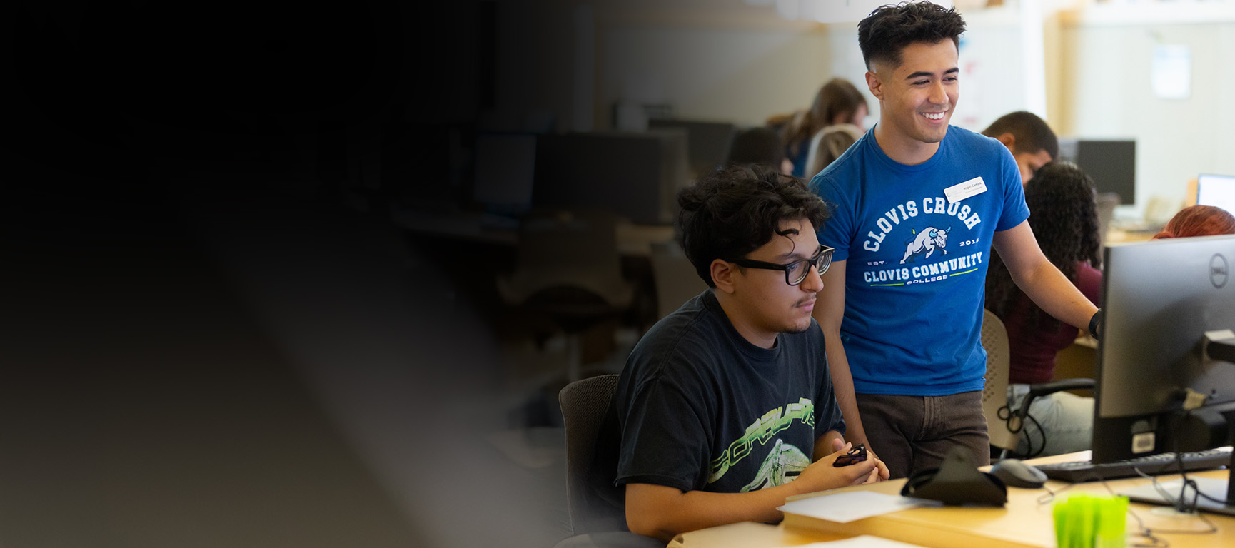 A young man helping a student on the computer