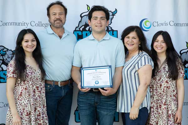 A male honors student celebrating commencement with his family