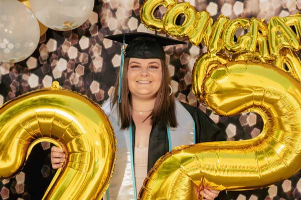 A student celebrating her graduation with balloons