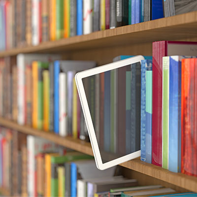An ebook tablet poking out of a stack of books