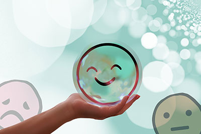a hand holding a happy face bubble with a green background