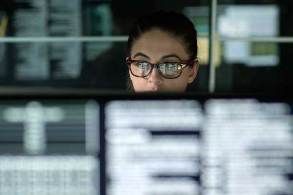 A female student researching at a computer. Her glasses reflect the data from the screen.