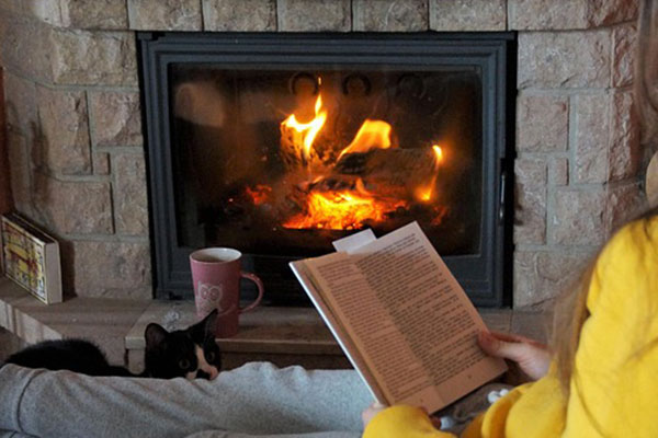 a person sits reading by a cozy fire